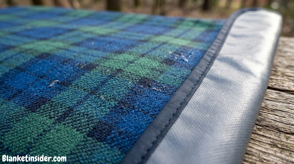 Close-up of outdoor blanket fabric texture — waterproof backing visible at edge